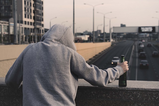 Mężczyzna stoi na moście i trzyma w dłoni piwo
